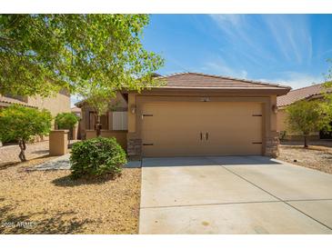 Tan two-car garage with stone accents and a well-maintained desert landscape at 22191 W Tonto St, Buckeye, AZ 85326