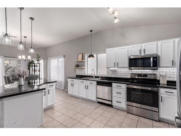 Bright kitchen features white cabinets, stainless steel appliances, black countertops, and tile flooring at 4109 E Chambers St, Phoenix, AZ 85040