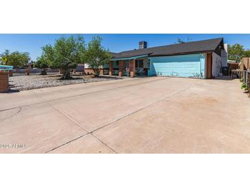 Charming single-story home featuring a light blue garage door and a wide driveway at 4402 N 79Th Dr, Phoenix, AZ 85033