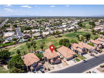 Expansive aerial view of a community with lush golf courses and houses with red tiled roofs under a clear, blue sky at 5953 W Aurora Dr, Glendale, AZ 85308