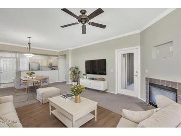 Open-concept living room features a fireplace, ceiling fan, and access to the kitchen at 19777 N 76Th St # 3238, Scottsdale, AZ 85255