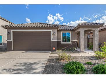 Charming home exterior featuring a well-maintained yard, two-car garage, and covered entryway at 19875 W Badgett Ln, Litchfield Park, AZ 85340