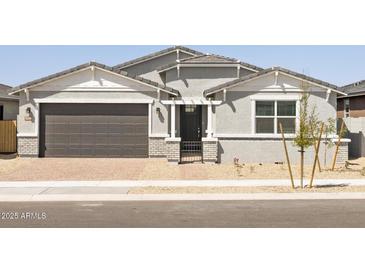 Charming single-story home featuring a grey exterior, brick accents, and a well-maintained front yard at 4032 S 176Th Dr, Goodyear, AZ 85338