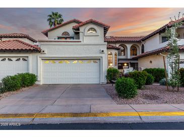 Charming home featuring a two-car garage, desert landscaping, and a Spanish tile roof at sunset at 11011 N 92Nd St # 1010, Scottsdale, AZ 85260