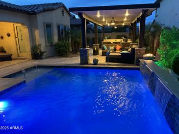 Backyard pool with a covered outdoor living space and a water feature offers an oasis for relaxation and entertainment at 2087 N Park St, Buckeye, AZ 85396