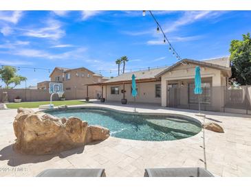 Resort-style backyard featuring a sparkling pool with rock accents, lush landscaping, and ample space for outdoor entertaining at 4968 E Westchester Dr, Chandler, AZ 85249