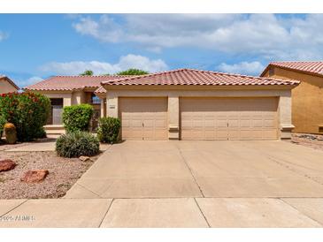 Charming home featuring a tile roof and a spacious three-car garage, complemented by lush landscaping at 9154 E Caribbean Ln, Scottsdale, AZ 85260