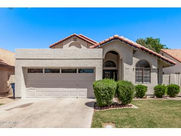 Charming single-story home with a two-car garage, desert landscaping and a red tile roof on a clear, sunny day at 113 S Ocean Dr, Gilbert, AZ 85233