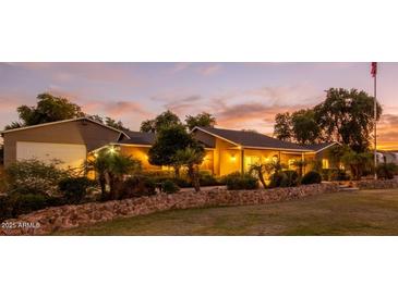 Charming single-story home with lush landscaping and warm exterior lighting at sunset at 14749 E Pecos Rd, Gilbert, AZ 85295