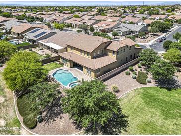 An aerial view displays a two-story home with a backyard pool and spa in a neighborhood with many other houses at 19943 E Strawberry Dr, Queen Creek, AZ 85142