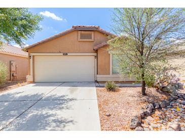 Tan single-story home featuring a two-car garage and desert landscaping at 41373 W Coltin Way, Maricopa, AZ 85138