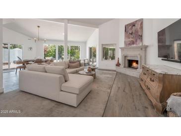 Inviting living room featuring a fireplace, vaulted ceilings, and seamless access to outdoor views at 8719 E San Marino Dr, Scottsdale, AZ 85258