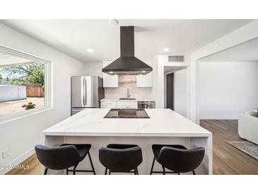 Bright kitchen with stainless steel appliances, white cabinets, and an island with seating at 1017 E Diana Ave, Phoenix, AZ 85020