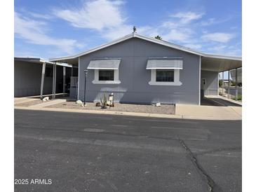 Charming gray home features awnings over the windows, desert landscaping, and a carport at 11411 N 91St Ave # 75, Peoria, AZ 85345