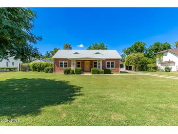 Charming brick home featuring a well-manicured lawn and a bright yellow front door at 16 W Colter St, Phoenix, AZ 85013
