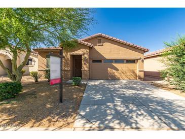 A tan single-story home with a red-tiled roof, a two-car garage, and a spacious driveway at 44188 W Cydnee Dr, Maricopa, AZ 85138
