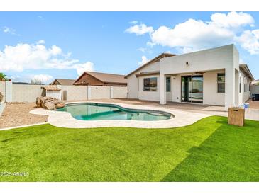 Inviting backyard pool with well-manicured lawn and desert landscaping at 18286 La Posada Ct, Gold Canyon, AZ 85118