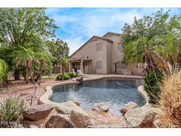 Landscaped back yard has a pool and relaxing water feature among lush greenery at 21373 N 94Th Ave, Peoria, AZ 85382