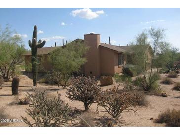 Tan single-story home featuring desert landscaping with native cactus, plants and trees at 27239 N 64Th Way, Scottsdale, AZ 85266