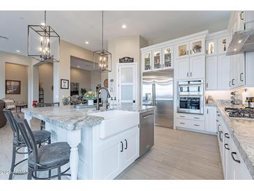 Modern kitchen featuring an island with a white farmhouse sink, stainless steel appliances, and barstool seating at 8021 E Jasmine St, Mesa, AZ 85207