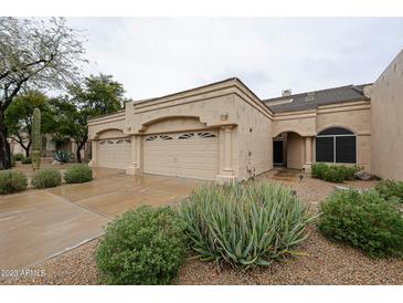 Beige single-story home showcasing a three-car garage, neutral color scheme, and desert landscaping at 8941 E Maple Dr, Scottsdale, AZ 85255