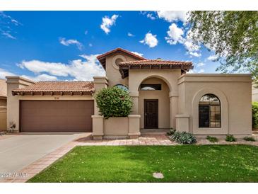 Charming single-story home featuring a Spanish tile roof, arched entryway, and manicured front lawn at 10511 N 87Th Way, Scottsdale, AZ 85258