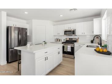 Bright white kitchen featuring stainless steel appliances, island, and modern finishes at 12506 W Corrine Dr, El Mirage, AZ 85335