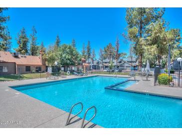 Community pool surrounded by lush greenery and lounge chairs, perfect for relaxing and enjoying the sunny weather at 14002 N 49Th Ave # 1040, Glendale, AZ 85306