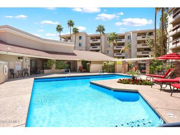 Community pool area with inviting blue pool, lounge chairs, and a well-maintained building backdrop at 4200 N Miller Rd # 228, Scottsdale, AZ 85251