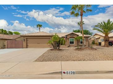 Charming home features a two-car garage, desert landscaping, and a tile roof at 6128 E Portia St, Mesa, AZ 85215