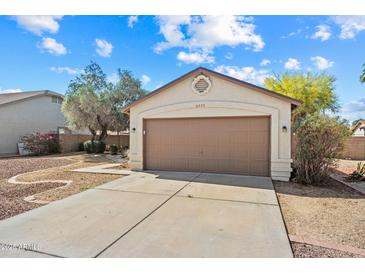 Single car garage with brown door, set in a desert landscaped front yard under a blue sky with clouds at 8335 W Pershing Ave, Peoria, AZ 85381