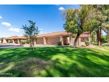 Well-maintained front yard with lush lawn and mature trees providing shade and curb appeal to the home at 945 N Pasadena -- # 62, Mesa, AZ 85201