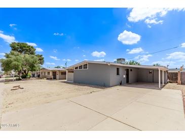 Charming single-story home featuring a large, paved driveway and desert landscaping under a bright, sunny sky at 2325 E Delgado St, Phoenix, AZ 85022