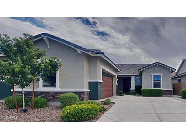 Charming single-story home featuring a well-manicured lawn, mature trees, and an attached two-car garage at 23497 S 212Th St, Queen Creek, AZ 85142