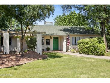Charming single story home with a green door, flag, and mature landscaping at 430 N Vineyard --, Mesa, AZ 85201