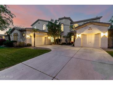 Stunning front exterior featuring a large driveway leading to three garages and beautiful desert landscaping at 4494 E Reins Rd, Gilbert, AZ 85297
