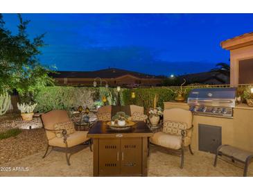 Inviting outdoor patio with comfortable seating, a dining table, a grill, and lush landscaping at 4200 E Narrowleaf Dr, Gilbert, AZ 85298