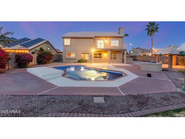 Resort-style backyard with a sparkling pool, lush landscaping, and a covered patio ideal for outdoor entertaining at 2022 N 124Th Dr, Avondale, AZ 85392