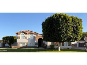 Charming two-story home featuring a red tile roof, stone accents, and a lush, green front lawn at 2431 E Laurel St, Mesa, AZ 85213
