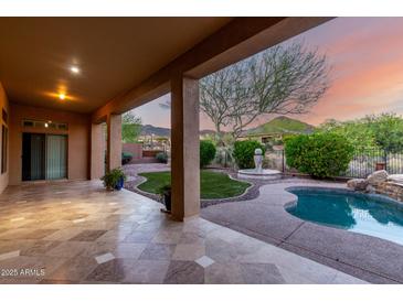 Spacious covered patio with travertine flooring, offering scenic backyard views at 41715 N River Bend Rd, Phoenix, AZ 85086