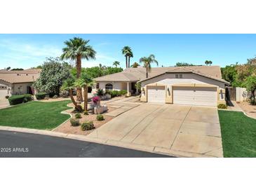 Charming home boasts a three-car garage, mature palm trees, and meticulous landscaping enhancing curb appeal at 4230 E Fountain St, Mesa, AZ 85205