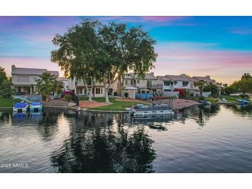 Waterfront homes feature manicured lawns, boat docks, and picturesque reflections on the serene lake, at sunset at 1267 E Chicago Cir, Chandler, AZ 85225