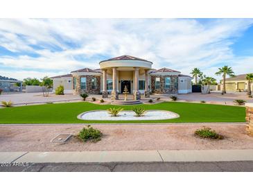 Stunning home featuring a circular driveway, portico entry, and lush green lawn with custom landscaping at 16368 W Watkins St, Goodyear, AZ 85338