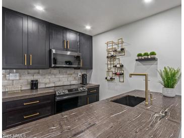 Modern kitchen features sleek black cabinetry with gold hardware, designer wine rack, and stone countertops at 5995 N 78Th St # 2078, Scottsdale, AZ 85250
