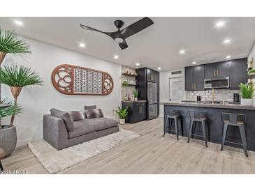 Open-concept living room features a plush gray sofa, unique wall art, and a modern kitchen bar at 5995 N 78Th St # 2078, Scottsdale, AZ 85250