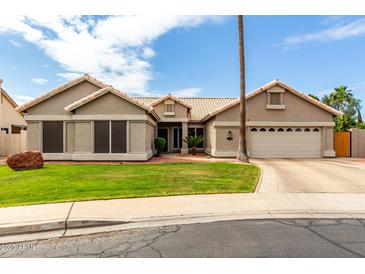 Charming single-story home with a well-manicured lawn, desert landscaping, and a two-car garage at 6577 W Abraham Ln, Glendale, AZ 85308