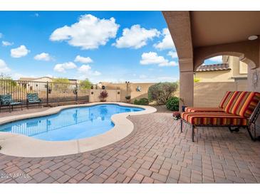 Inviting pool area with a lounge chair on a brick patio, surrounded by desert landscaping at 13648 W Jesse Red Dr, Peoria, AZ 85383