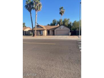 Single-story home with a two-car garage and palm trees in the front yard, under a clear blue sky at 5219 W Eugie Ave, Glendale, AZ 85304