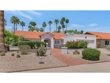 Charming Southwestern home features a red tile roof, lush landscaping, and a welcoming brick pathway at 8666 E Cheryl Dr, Scottsdale, AZ 85258