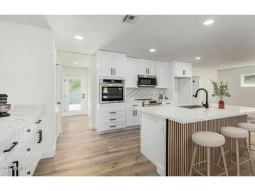 Modern white kitchen boasts stainless steel appliances, a marble backsplash, and a stylish kitchen island at 1313 N 71St St, Scottsdale, AZ 85257